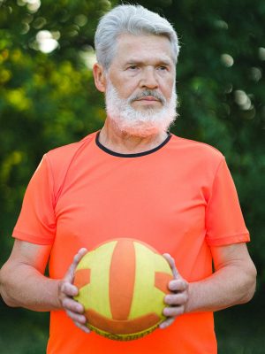 Serious aged man doing exercise with ball